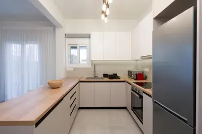 a kitchen with white cabinets and a wooden counter top at LIV - Elegant City Stay in Pagrati in Athens