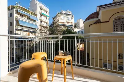 two yellow stools sitting on a balcony with buildings at LIV - Elegant City Stay in Pagrati in Athens