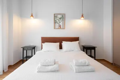 a bedroom with a white bed with two side tables at LIV - Captivating Apartment in Pagrati in Athens