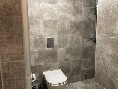 a bathroom with a toilet and a tiled wall at Sani Entire Flat near Syntagma Square in Athens