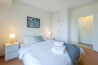 a white bedroom with a large bed and two lamps at Glyfada central seaside apartment in Athens