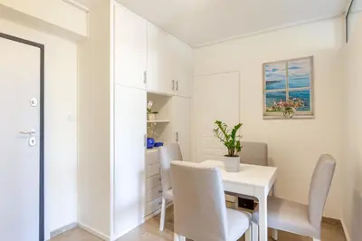 a white dining room with a white table and chairs at Glyfada central seaside apartment in Athens