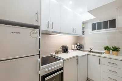 a kitchen with white cabinets and a refrigerator at Glyfada central seaside apartment in Athens