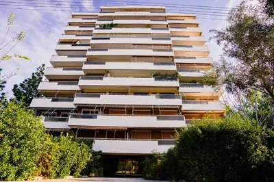 a tall white apartment building with trees in front of it at Glyfada central seaside apartment in Athens