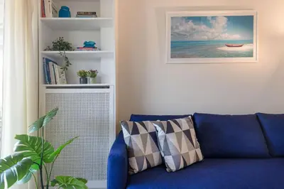 a blue couch in a living room with a book shelf at Glyfada central seaside apartment in Athens