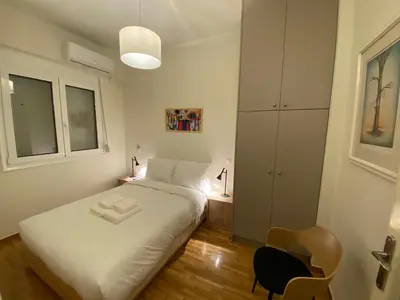 a small bedroom with a white bed and a chair at Irene's studio in Athens