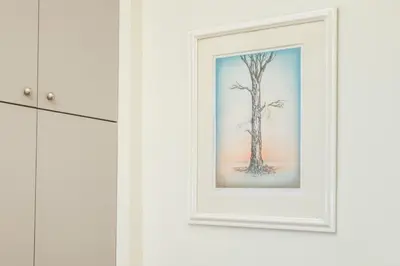 a picture of a tree in a white frame on a wall at Irene's studio in Athens