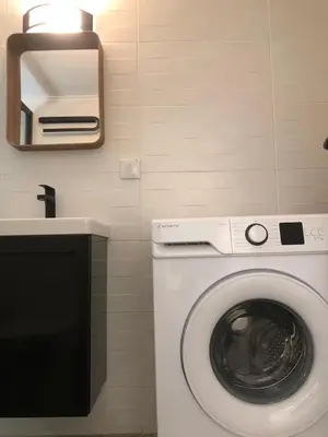 a washing machine in a bathroom with a mirror at AIOLOS Pagrati Athens Hilton near METRO station in Athens