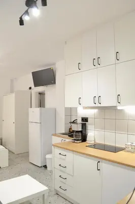 a kitchen with white cabinets and a white refrigerator at AIOLOS Pagrati Athens Hilton near METRO station in Athens