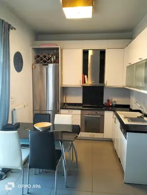a kitchen with white cabinets and a table with chairs at Minimal flat in Kalithea in Athens
