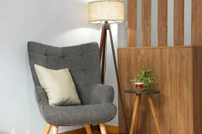 a floor lamp next to a chair with a pillow at Chrysas apartment in Athens