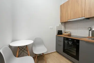 a kitchen with white chairs and a black oven at Chrysas apartment in Athens