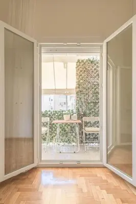 an empty room with a large window and a table at Central Cosy quite 28sm 5th floor balcony over garden 500m Metro Evangelismos in Athens