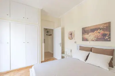 a bedroom with a white bed and a painting on the wall at Central Cosy quite 28sm 5th floor balcony over garden 500m Metro Evangelismos in Athens