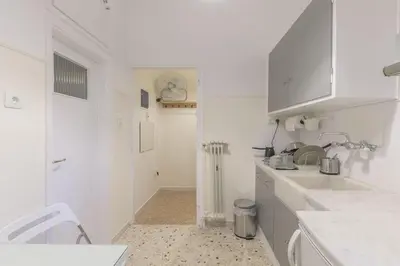 a white kitchen with white cabinets and a sink at Central Cosy quite 28sm 5th floor balcony over garden 500m Metro Evangelismos in Athens