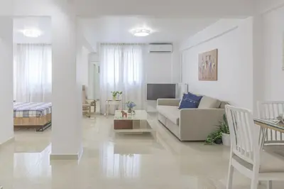 a white living room with a couch and a table at Golden Studio 47sm in Athens Central Pangrati 1km Metro Evangelismos in Athens