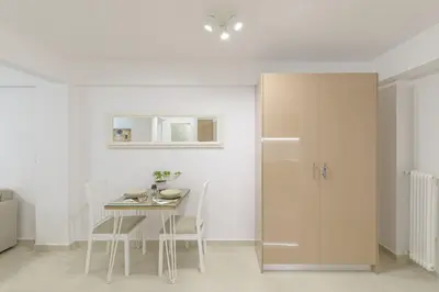 a white kitchen with a table and chairs and a refrigerator at Golden Studio 47sm in Athens Central Pangrati 1km Metro Evangelismos in Athens