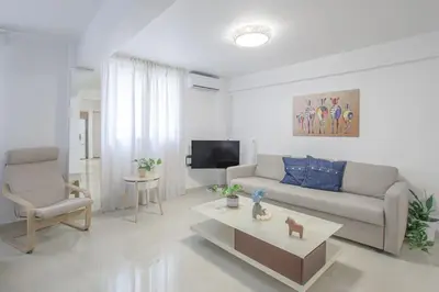 a white living room with a couch and a tv at Golden Studio 47sm in Athens Central Pangrati 1km Metro Evangelismos in Athens