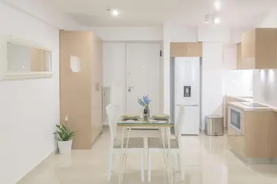 a white kitchen with a table and white appliances at Golden Studio 47sm in Athens Central Pangrati 1km Metro Evangelismos in Athens