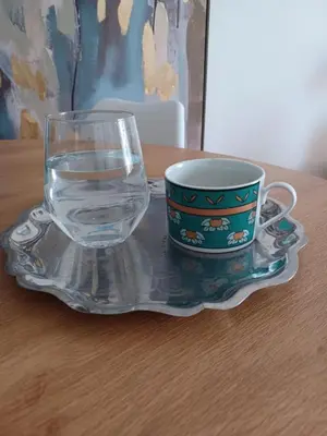 a glass of water and a cup on a plate at Modern 2 bedroom Apartment near Kallimarmaro and Alsos in Athens