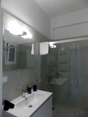 a white bathroom with a sink and a shower at Modern 2 bedroom Apartment near Kallimarmaro and Alsos in Athens