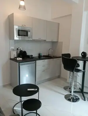 a kitchen with white cabinets and two chairs and a table at Funky & trendy 1 BDR aparment in Athens