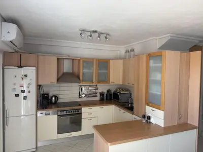 a kitchen with wooden cabinets and a white refrigerator at Sea View Serenity in Athens in Anavissos