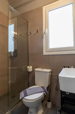 a bathroom with a toilet and a sink and a window at Jacuzzi Patio & Acropolis view 2-BD Retreat in Athens