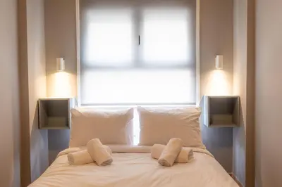 a bed with two pillows in front of a window at Jacuzzi Patio & Acropolis view 2-BD Retreat in Athens