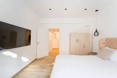 a white bedroom with a large bed and a television at Alma Suite - close to Acropolis in Athens