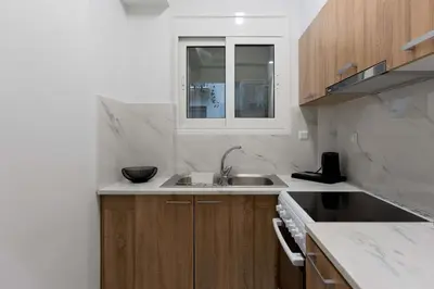 a white kitchen with a sink and a window at Phaedrus Living Kolonaki Maple Residence in Athens