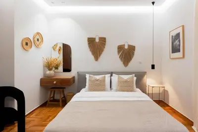 a bedroom with a bed with white walls and wooden floors at Phaedrus Living Kolonaki Maple Residence in Athens