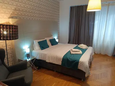 a bedroom with a large bed and a chair at Plaka Hideaway Suite in Athens