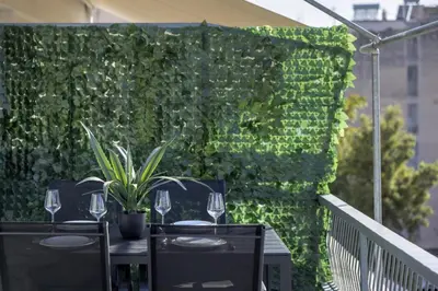 a patio with two tables with wine glasses and a green wall at Modern Renovated Apartment in Metaksourgio in Athens