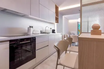 a kitchen with white cabinets and a counter with chairs at Phaedrus Living Athens Luxury Residences Champagne in Athens