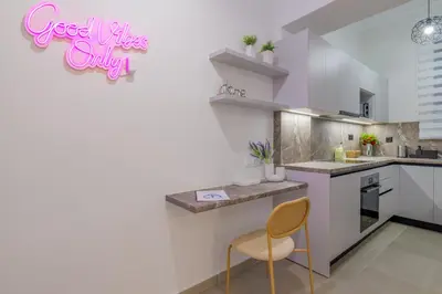 a kitchen with white cabinets and a yellow chair at Koukaki Cielo Villa10 -Pvt Yard 3BR 8ppl -10min Metro Acropolis in Athens