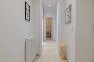 a hallway with white walls and a table and a stool at Koukaki Cielo Villa10 -Pvt Yard 3BR 8ppl -10min Metro Acropolis in Athens