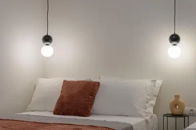a white bedroom with a bed with two pendant lights at Koukaki Cielo Villa10 -Pvt Yard 3BR 8ppl -10min Metro Acropolis in Athens