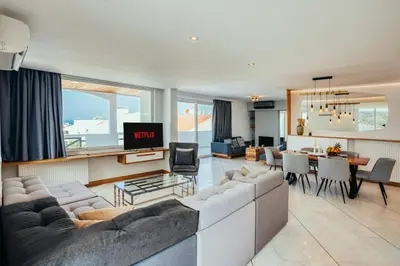 a living room with a couch and a dining room at Grand Sea View Apartment 3' from Kavouri Beach in Athens