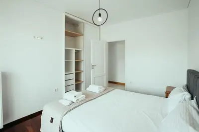 a white bedroom with a bed and a closet at Grand Sea View Apartment 3' from Kavouri Beach in Athens