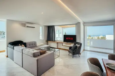 a living room with a couch and a tv at Grand Sea View Apartment 3' from Kavouri Beach in Athens