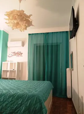 a bedroom with a bed and a blue curtain at 1970s Athenean Apartment in Athens