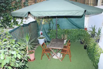 a table and two chairs under a green umbrella at Cozy Mezonette near City Center Athens near Metro in Athens
