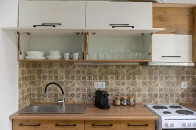 a kitchen with white cabinets and a sink and a stove at Entire Apt, Maisonette, 1 Bedroom in Athens