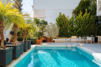 a swimming pool with palm trees and a table at Serena Calm Pool House in Athens