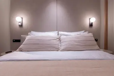 a bed with white sheets and two lights on it at Phaedrus Living Athens Luxury Residences Ivory in Athens