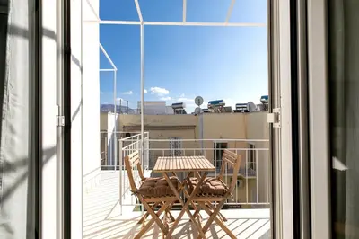 a table and chairs on a balcony with a view at Helios Apartment by A&A Residences in Athens