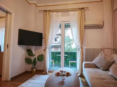 a living room with a couch and a table and a window at The Golden Embrace in Athens