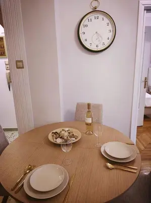 a table with plates and glasses and a clock on the wall at The Golden Embrace in Athens