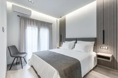 a bedroom with a large bed and a chair at EN Suites Stylish & Comfort Stay near Acropolis in Athens